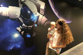 Mum holding a baby near astronaut picture in Finder office