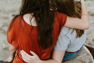 two women hugging facing away from camera