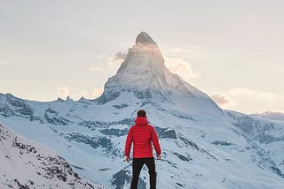 A person in winter climbing gear looking at a mountain top they intend to ascend