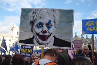 Image of a clown face painted on a protest sign.