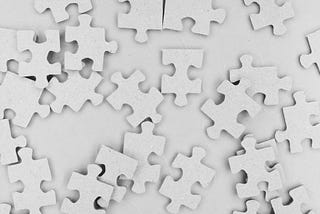 A picture of scattered white puzzle pieces on a white background.