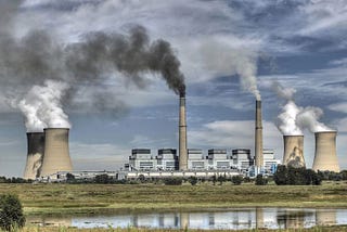 A landscape of a power plant in South Africa with various chimneys releasing smoke and steam