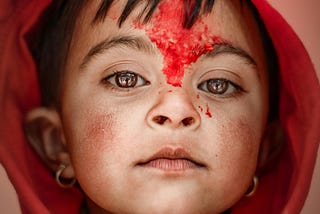 A girl in a red hoodie with red fluid smeared on her face