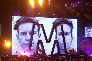 Video wall featuring Andrew Fletcher of Depeche Mode behind a large M