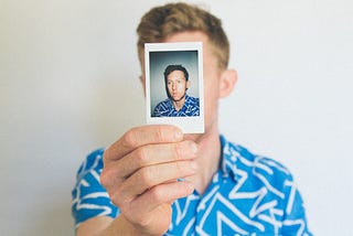 Man holding a photo of himself in front of his face