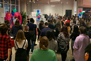 A room filled with many people watching someone speak on a stage.