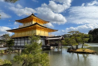 The Golden Pavilion in Kyoto against a blue cloudy sky.