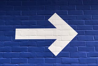 White arrow painted on a blue wall