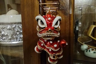 A small red Chinese lion hanging in front of a brown cabinet