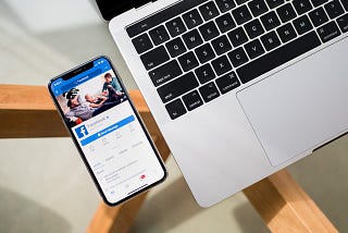 Facebook business on a mobile beside a laptop