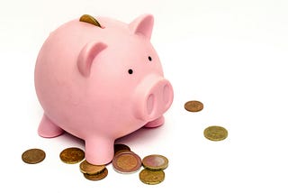 Pink piggy bank surrounded by gold coins.