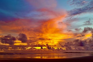 A dazzling display of sunset colours fills a cloudy coastal sky