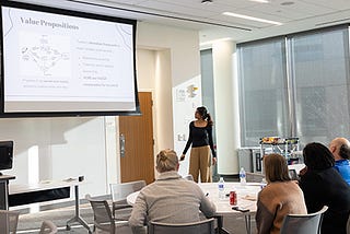 A student presents their business pitch to a panel of judges in a competition.