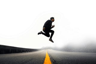 man jumping above gray and yellow concrete road at daytime