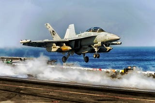 A Navy fighter jet taking off from an aircraft carrier