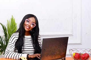 A female UX Designer wearing reading glasses and smiling at her computer