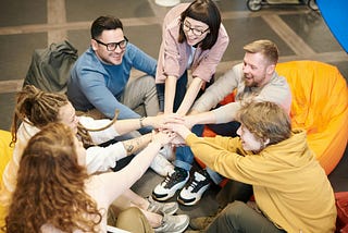 Photo of a team of people joining hands together.