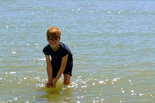 Smiling child in sparkling sea ready to splash