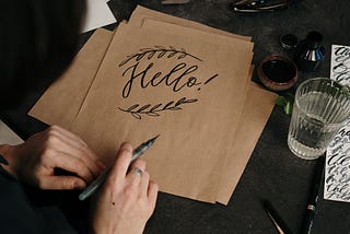 The word “Hello” written in calligraphy on a cardstock.