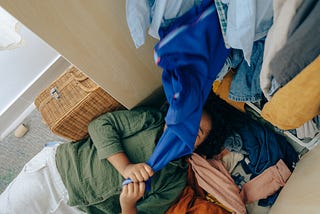 Anonymous black girl lying on stack of clothes. Credit goes to Ketut Subiyanto from Pexel