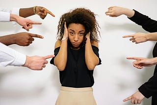 People pointing a finger at a scared woman.