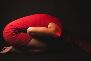 Woman in a red dress doubles over in pain