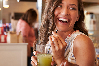 Two young women, one white, one black, sitting at a table in a restaurant and enjoying a fun, lively conversation.