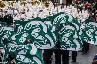 Colorado State University marching band and color guard waving green and white ram flags.