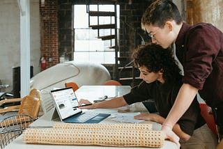 Man and woman looking at a laptop on a table. Photo by Microsoft 365 on Unsplash