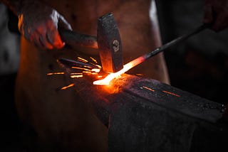Blacksmith using hammer with forge.