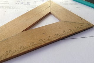 An image of a measuring wooden triangle that depicts the manual art of problem solving