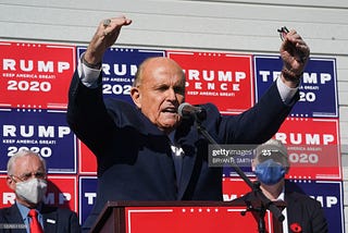 Rudy Giuliani, evangelizes the cult of Trump at a news conference in the parking lot of a landscaping company on 11/7/20.