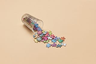 glass cup that that tipped over, spilling out colorful puzzle pieces