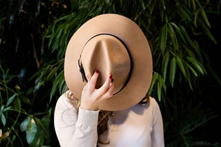 A woman covering her face with a hat