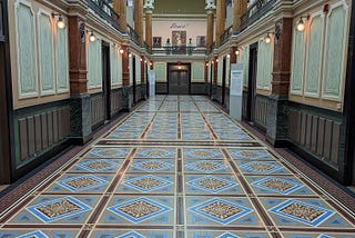 Ornately tiled floor in a long hallway leading to a doorway