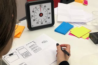 Solo designer sketching with a time timer and post-it notes