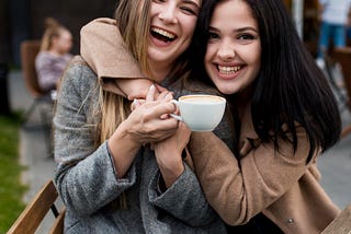 Young woman being hugged by her friend