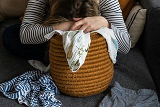 Woman slumped over laundry basket