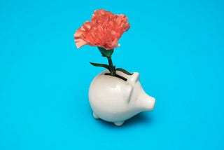 A piggybank with a flower in it.