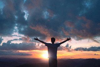 Person greeting the sunrise/sunset with outstretched arms.