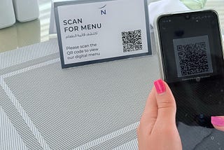 A diner scans a QR code on a restaurant menu, symbolizing how blockchain technology could make food sourcing transparent and safer.