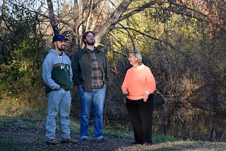Three people stand in the woods