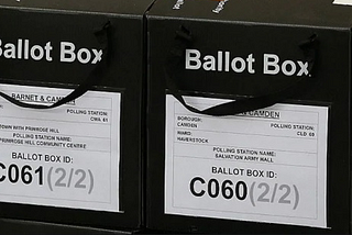 Ballot boxes in black with British voting authorities on them.