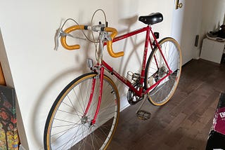 A vintage red bike with gold taped, curly handlebars
