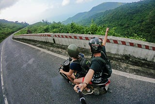 2 young people riding a scooter in se Asia