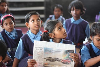 Children reading news paper.