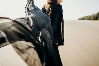 Woman in black walking on a beach