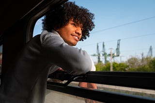 Young boy leaning against a train window, gazing outside with a look of wonder and excitement.