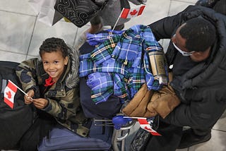 A child holds a small Canadian flag and is all smiles as he and his family arrive at HFX Stansfield airport from war torn Ukraine