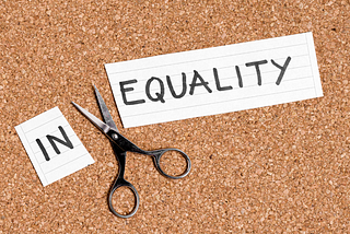 Photo showing the word “inequality” written on a piece of paper and cut between the N and E